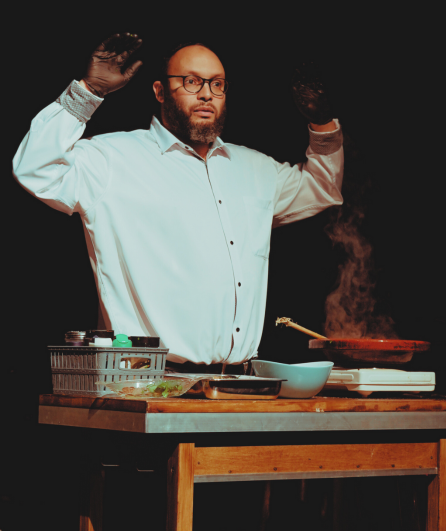 Affiche du spectacle. Un homme devant une cuisinière, les mains en l’air.